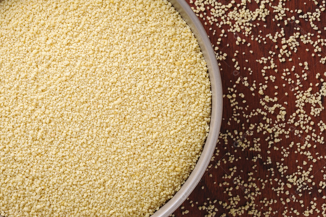 Flocos de cuscuz em tigela rústica e fundo de madeira. Vista do topo. Espaço para texto.