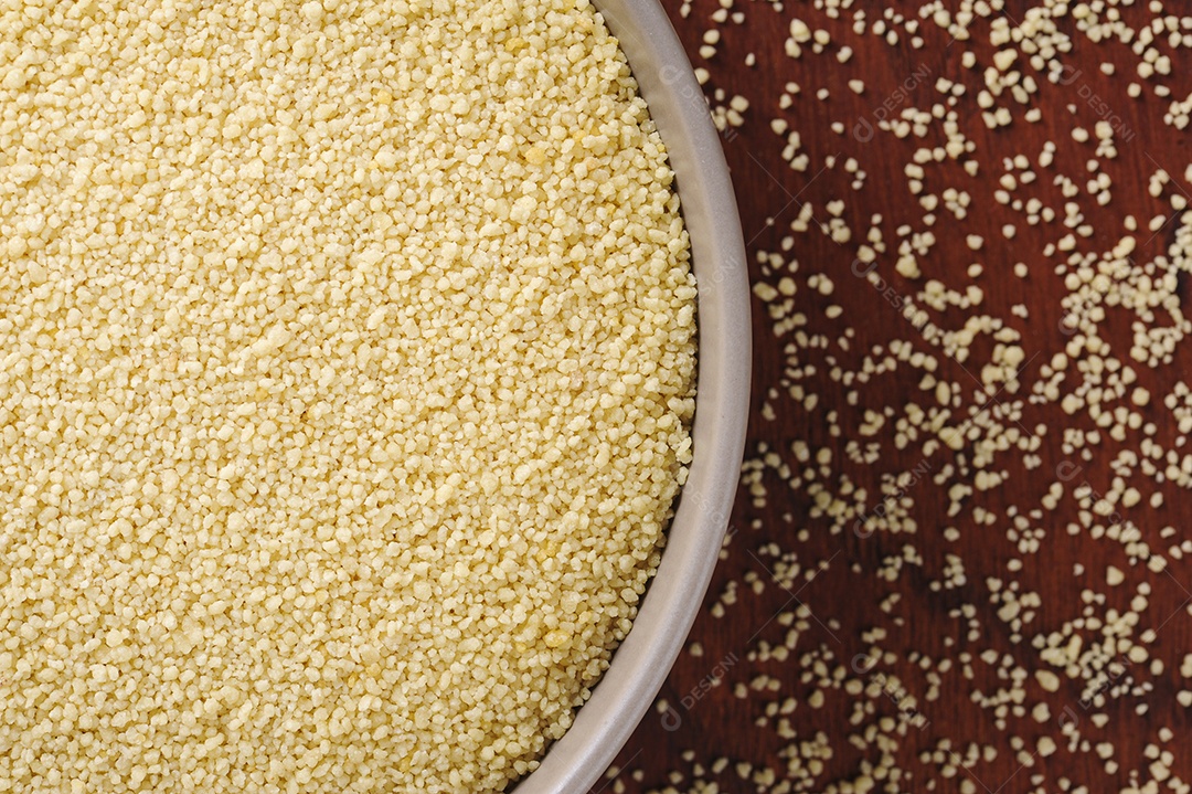 Flocos de cuscuz em tigela rústica e fundo de madeira. Vista do topo. Espaço para texto.