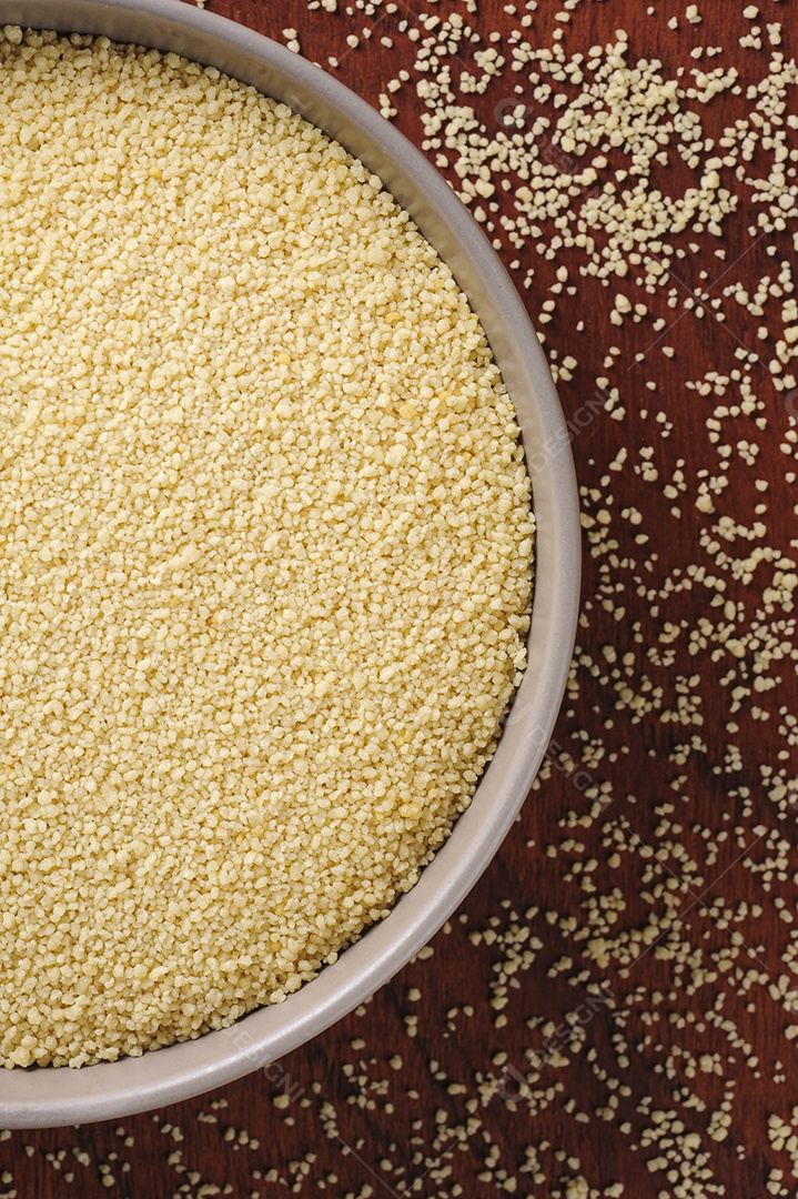 Flocos de cuscuz em tigela rústica e fundo de madeira. Vista do topo. Espaço para texto.