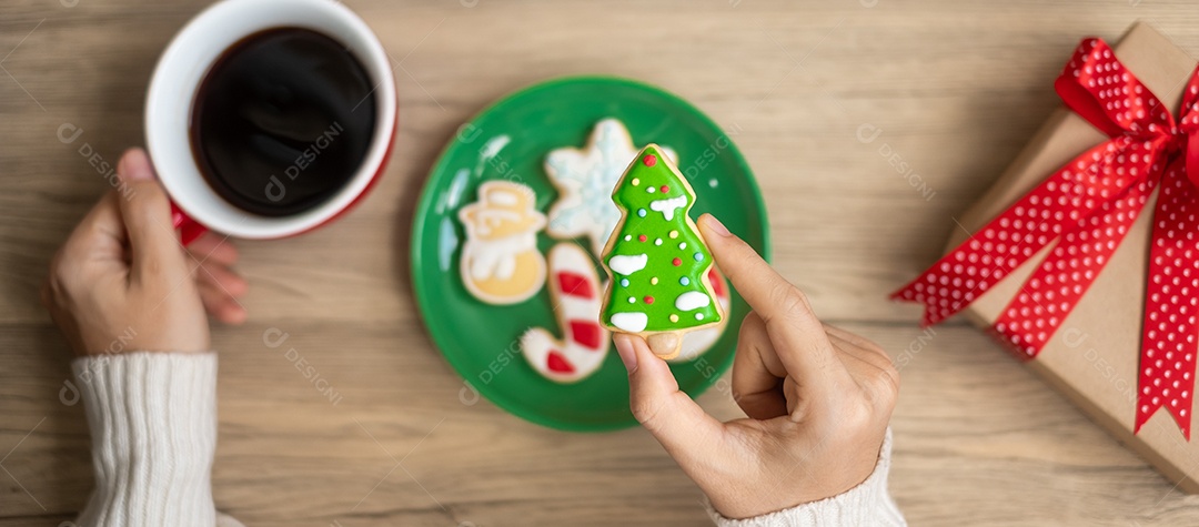 Feliz Natal com a mão de uma mulher segurando a xícara de café e caseira