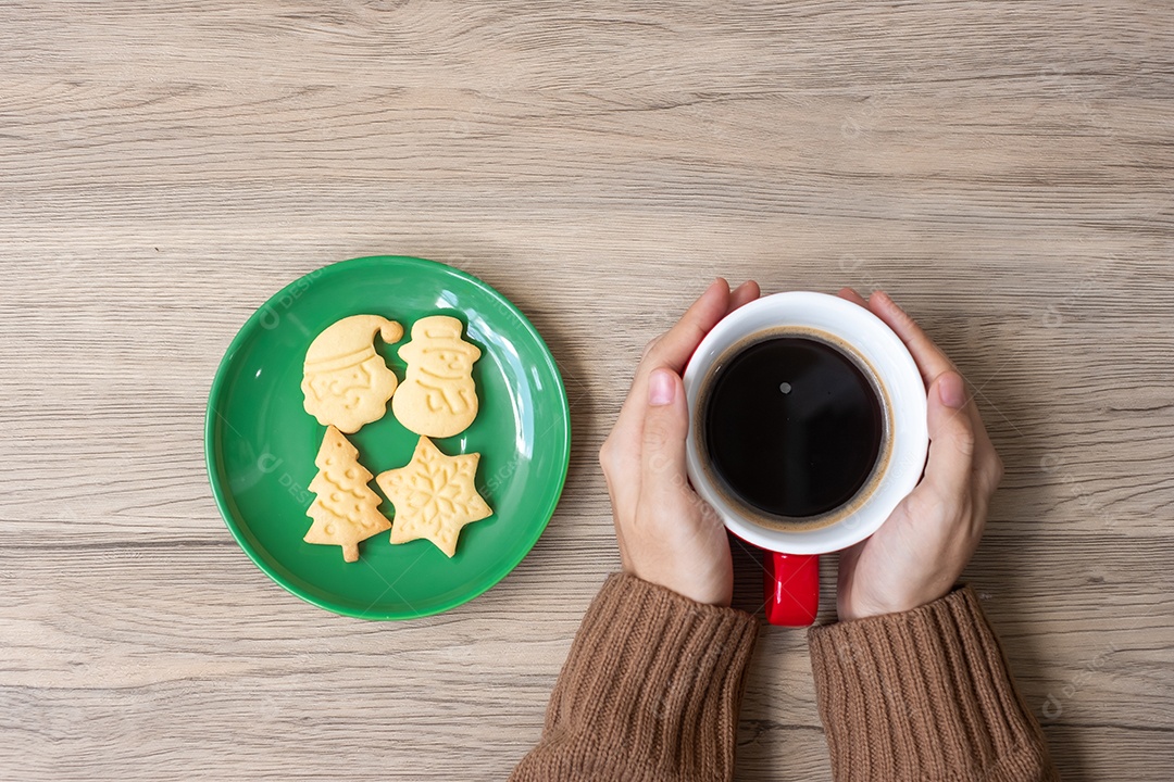 Feliz Natal com a mão de uma mulher segurando a xícara de café e caseira