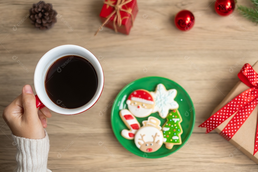 Feliz Natal com a mão de uma mulher segurando a xícara de café e caseira