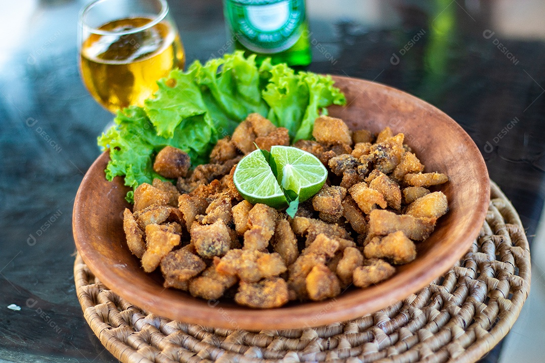 Prato de comida torresmo frito com limão cortado ao meio