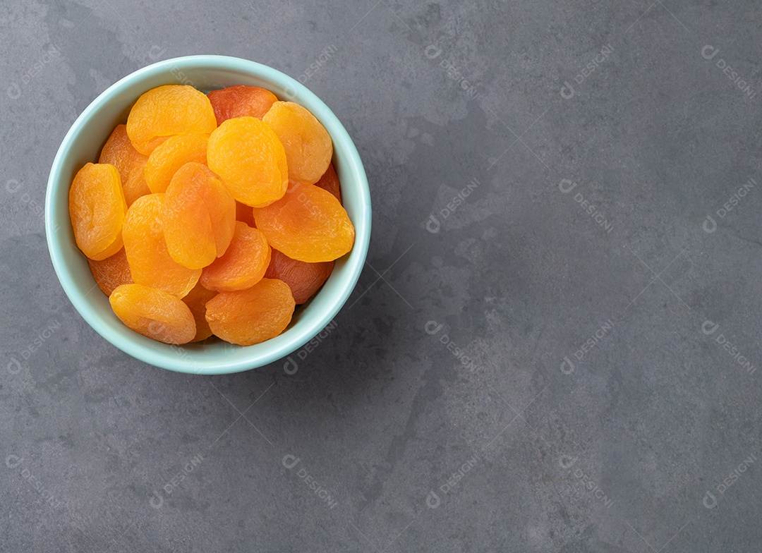Damascos secos em uma tigela sobre fundo de pedra