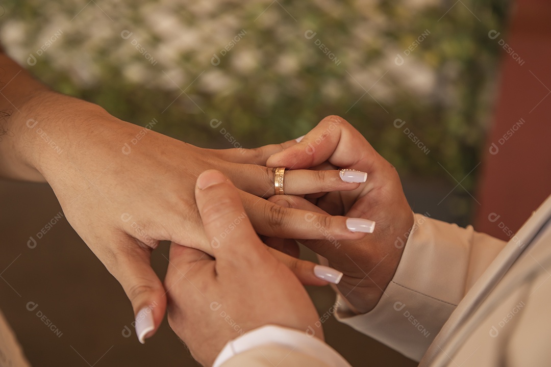 Noivo colocando aliança e mãos de sua esposa