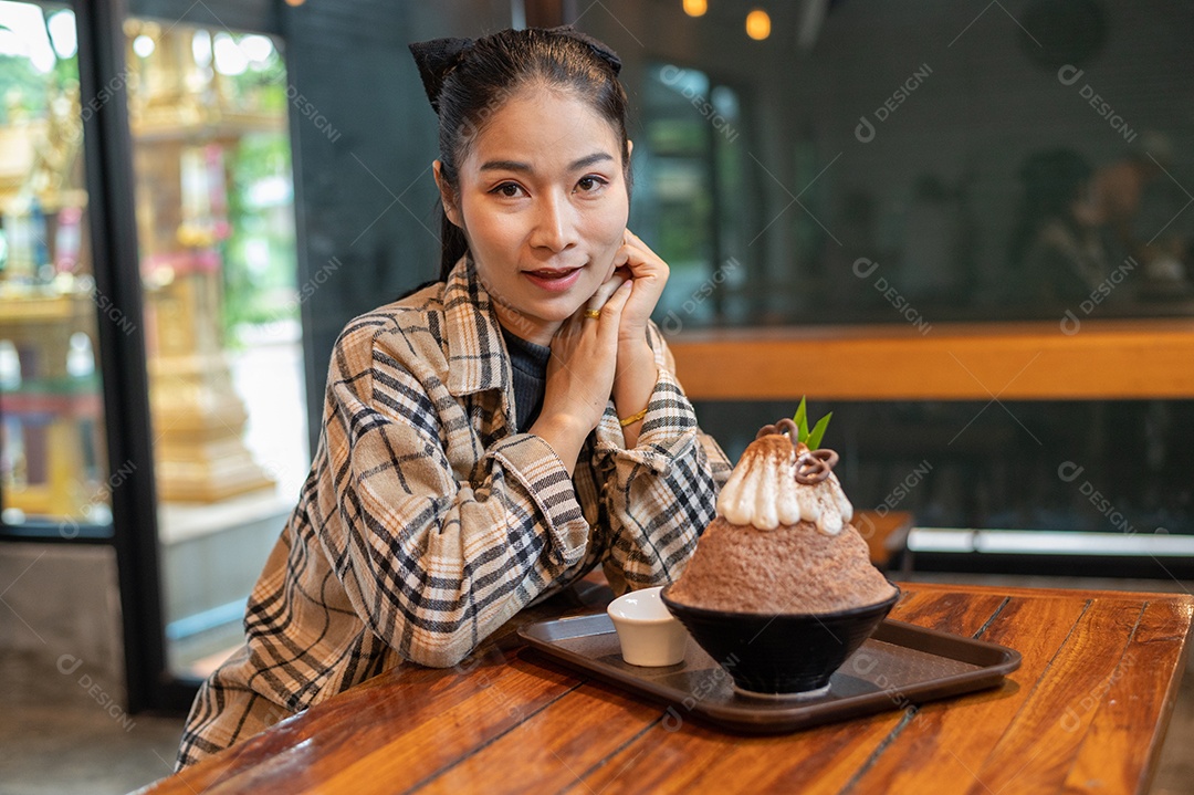 Mulher coreana sentada em lanchonete comendo sobremesa gelada - bingsu do chocolate