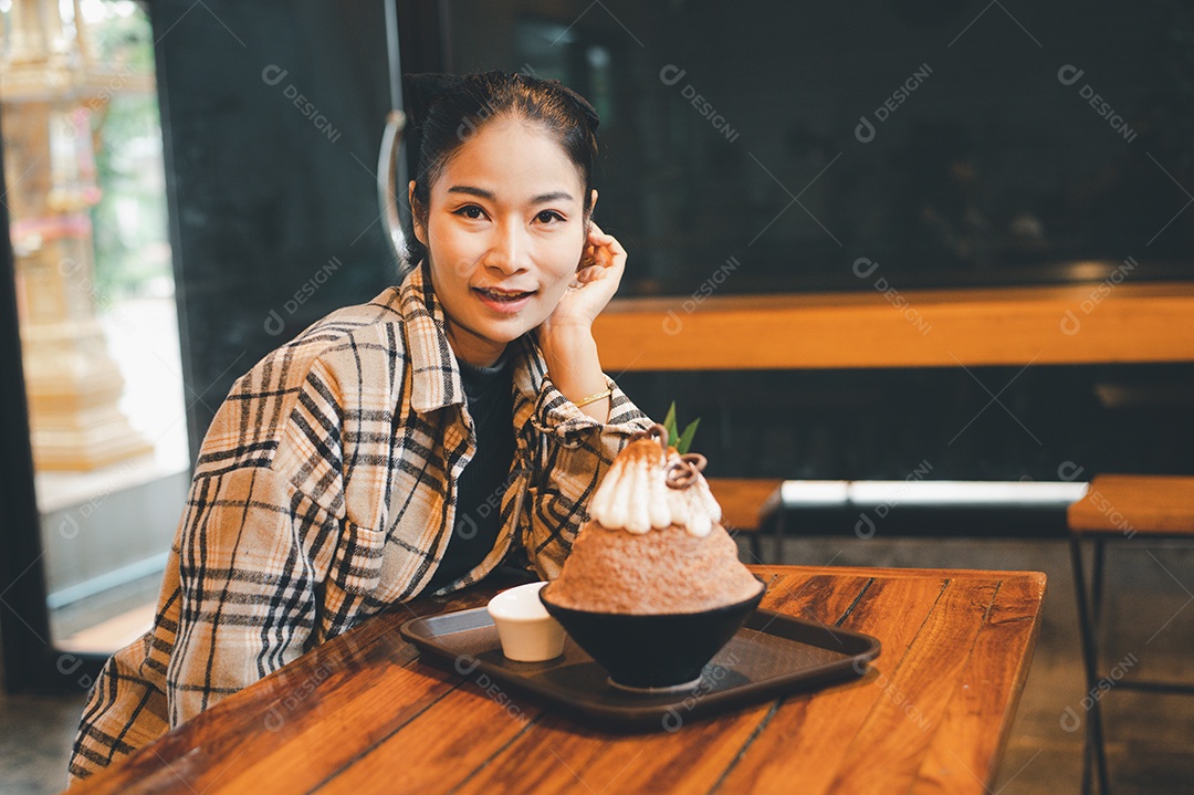 Mulher coreana sentada em lanchonete comendo sobremesa gelada - bingsu do chocolate