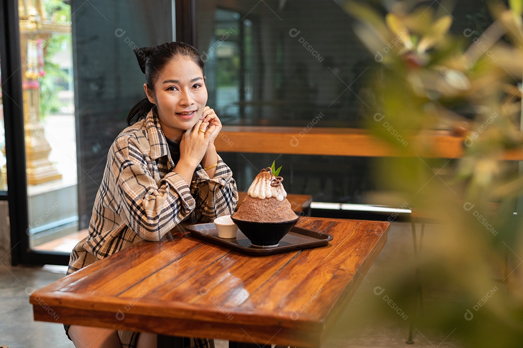 Mulher coreana sentada em lanchonete comendo sobremesa gelada - bingsu do chocolate