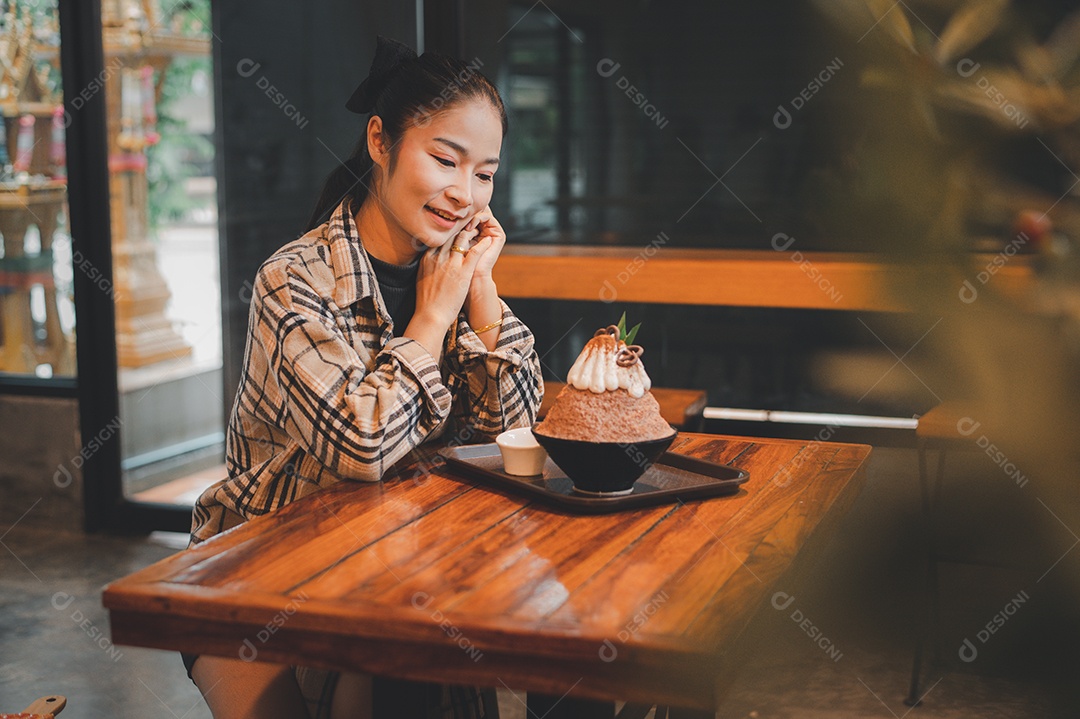 Mulher coreana sentada em lanchonete comendo sobremesa gelada - bingsu do chocolate