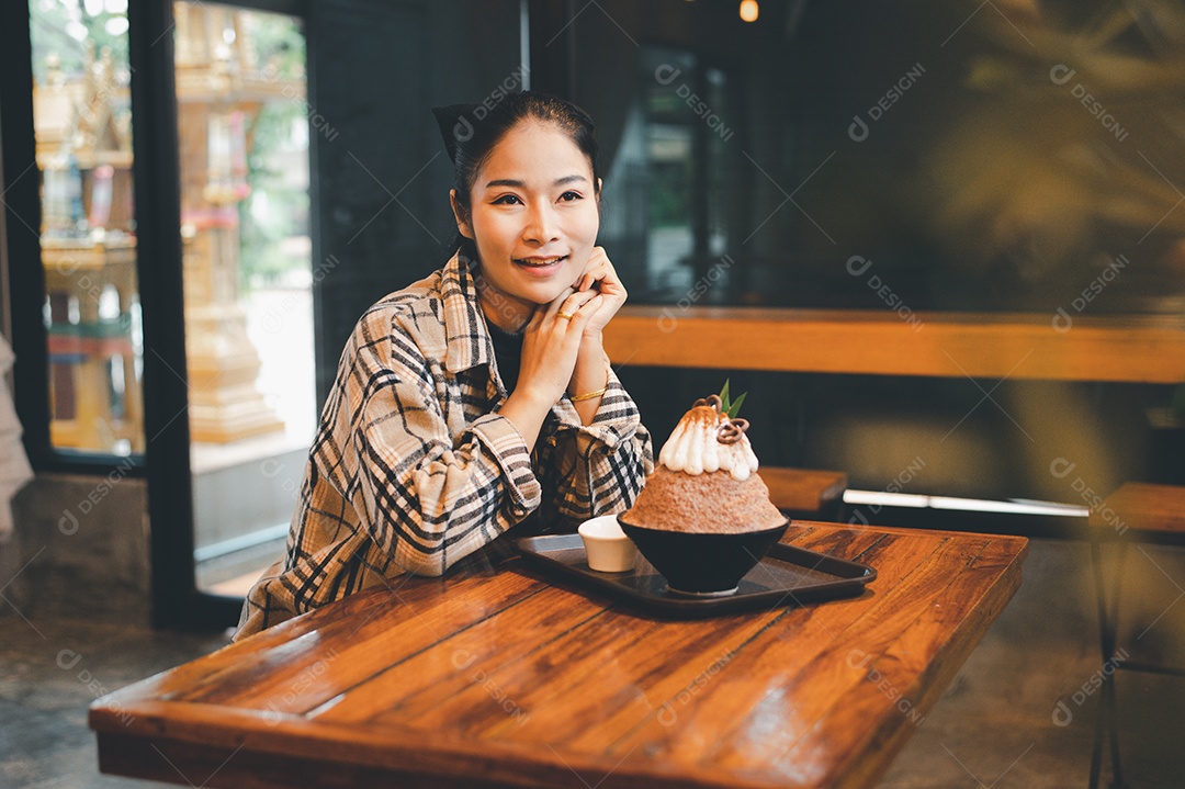 Mulher coreana sentada em lanchonete comendo sobremesa gelada - bingsu do chocolate