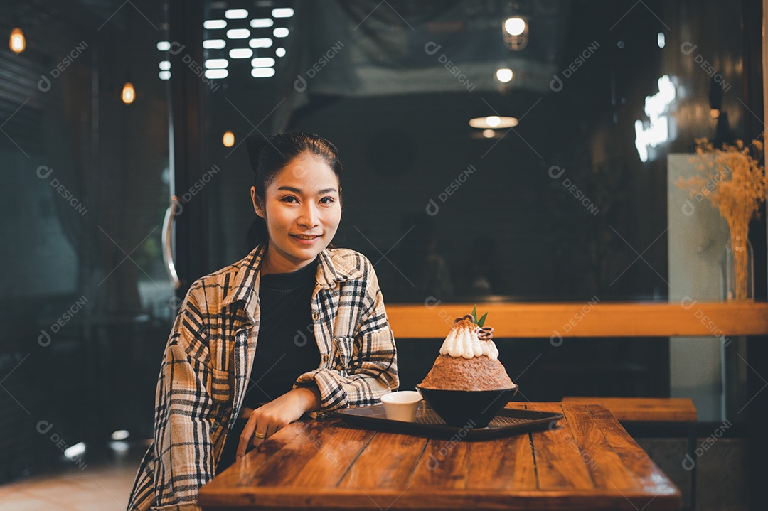 Mulher coreana sentada em lanchonete comendo sobremesa gelada - bingsu do chocolate