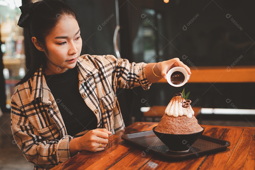 Mulher coreana sentada em lanchonete comendo sobremesa gelada - bingsu do chocolate