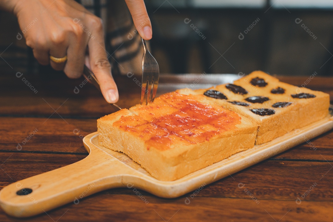 Pessoa cortando torrada com geleia e uvas passas