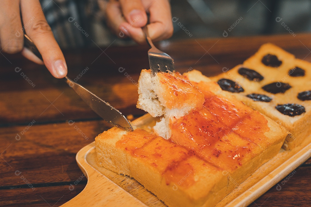 Pessoa cortando torrada com geleia e uvas passas
