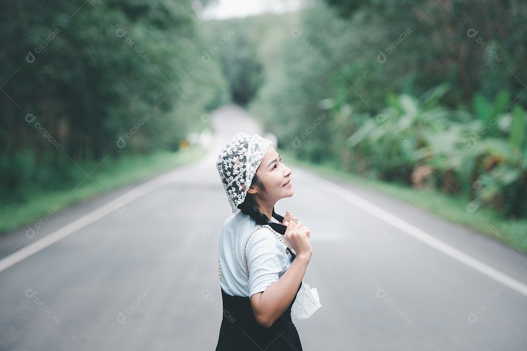 Mulher feliz em estrada, cercada de uma floresta verde
