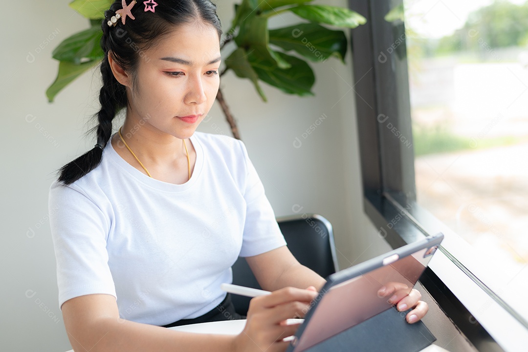 Mulher asiática sentada segurando um tablet