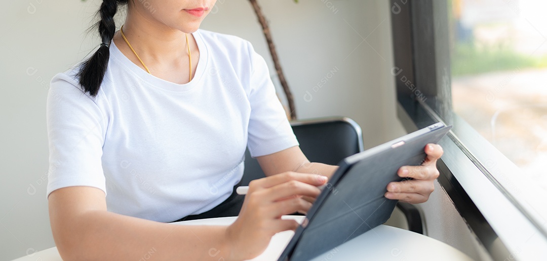 Mulher asiática sentada segurando um tablet