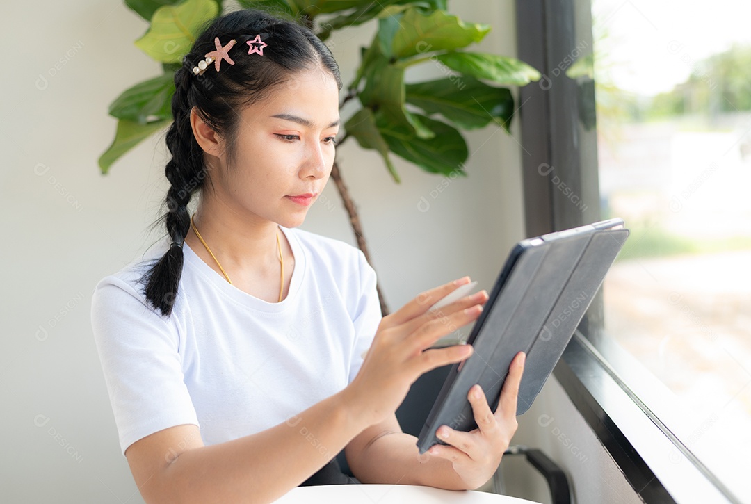 Mulher asiática sentada segurando um tablet