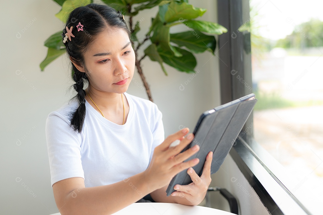 Mulher asiática sentada segurando um tablet