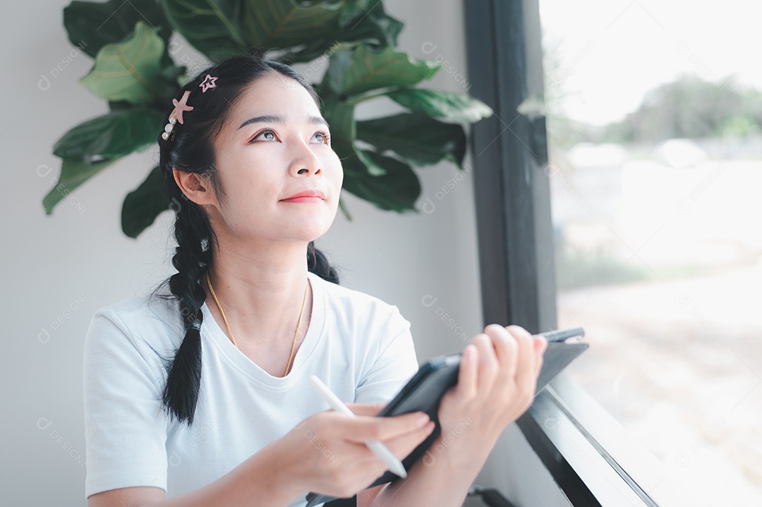 Mulher asiática sentada segurando um tablet