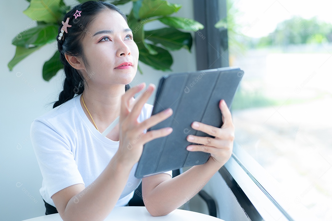 Mulher asiática sentada segurando um tablet