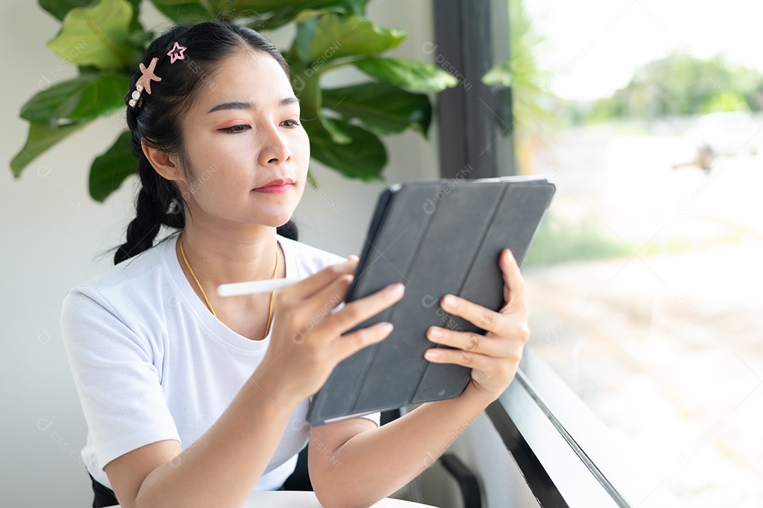 Mulher asiática sentada segurando um tablet