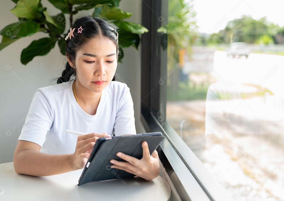 Mulher asiática sentada segurando um tablet