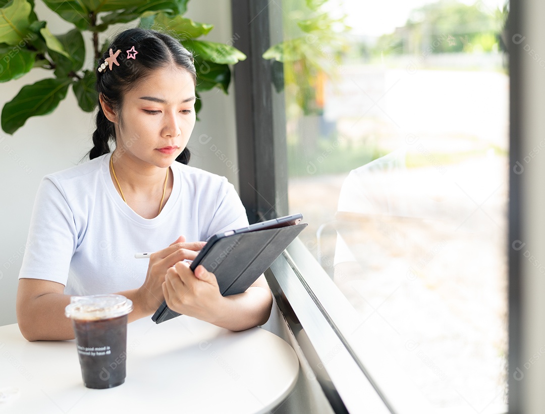 Mulher asiática sentada segurando um tablet
