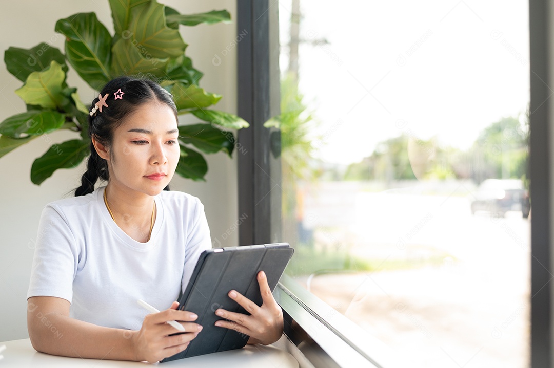 Mulher asiática sentada segurando um tablet