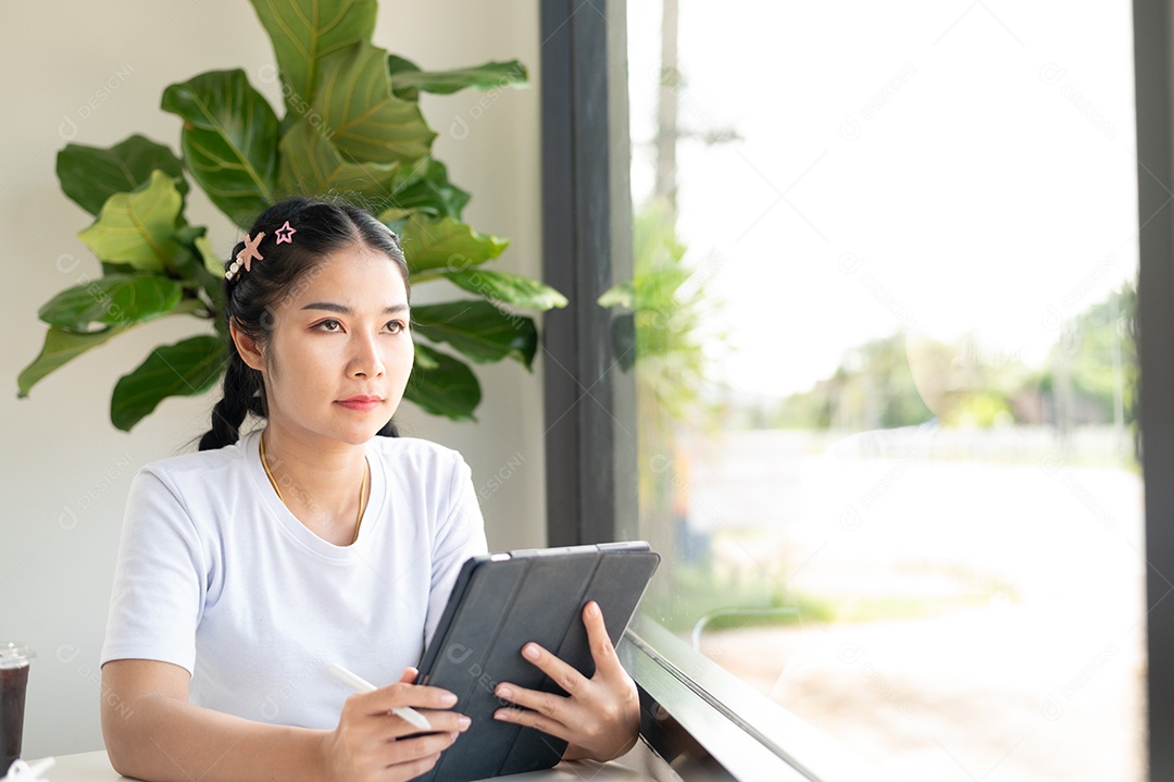 Mulher asiática sentada segurando um tablet