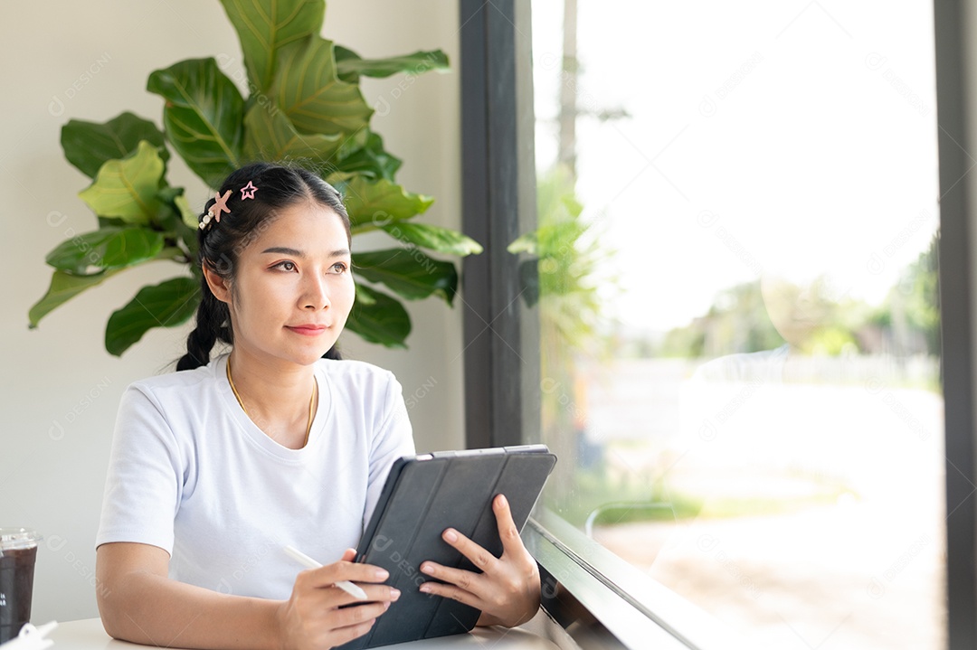 Mulher asiática sentada segurando um tablet