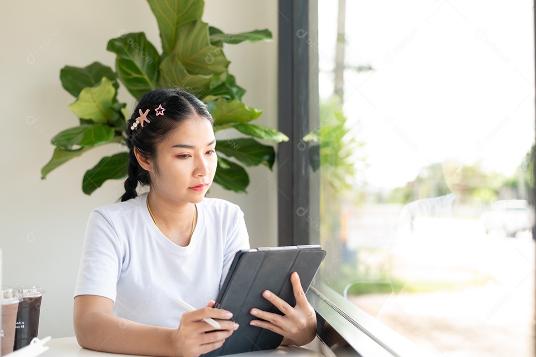 Mulher asiática sentada segurando um tablet