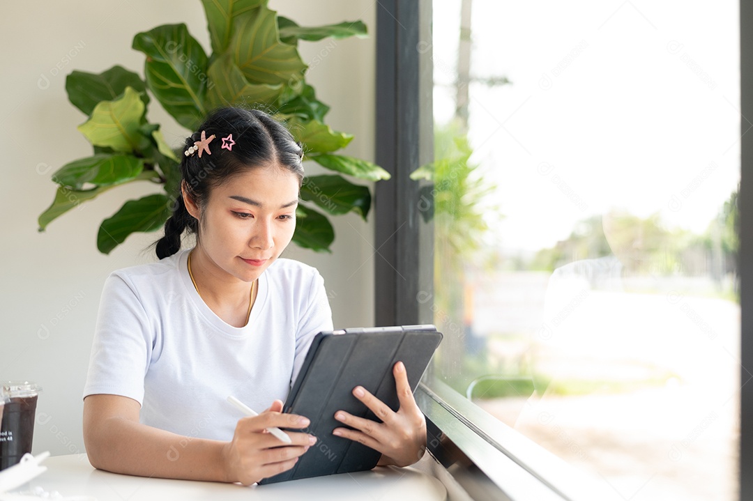 Mulher asiática sentada segurando um tablet