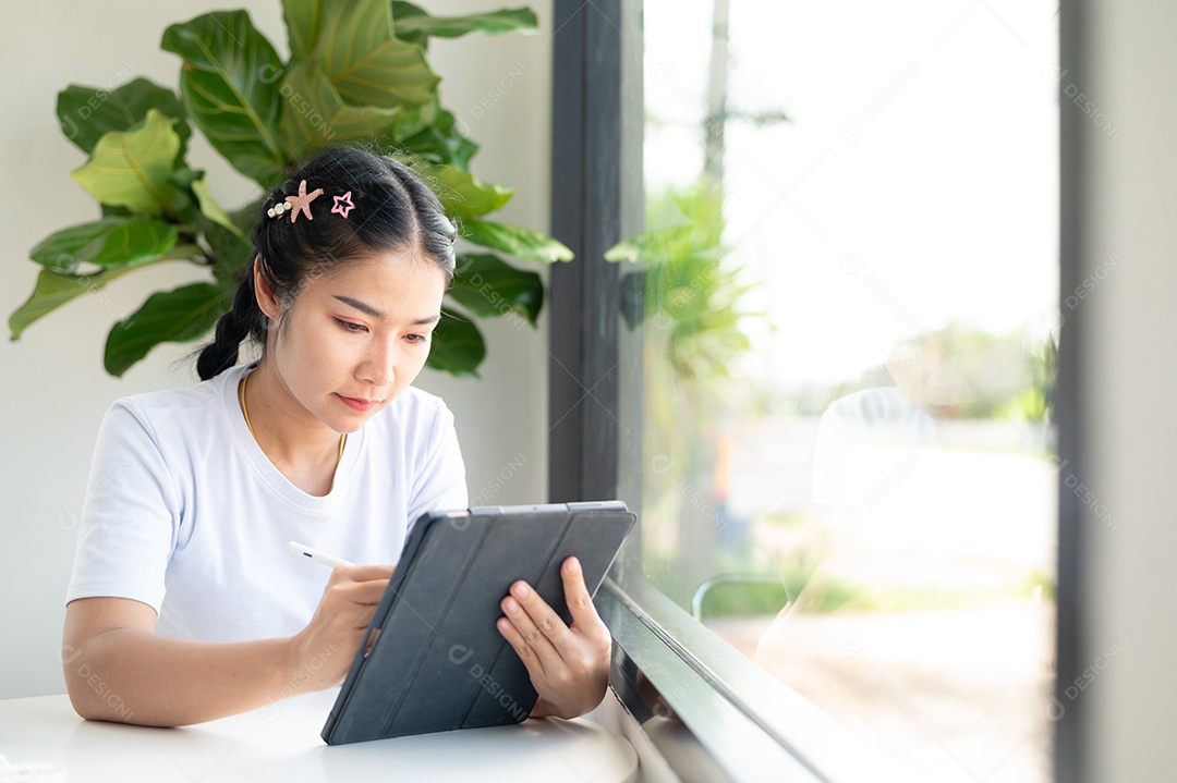 Mulher asiática sentada segurando um tablet