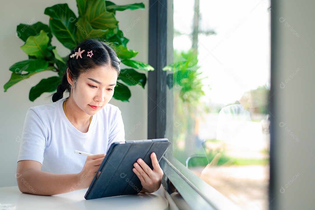 Mulher asiática sentada segurando um tablet