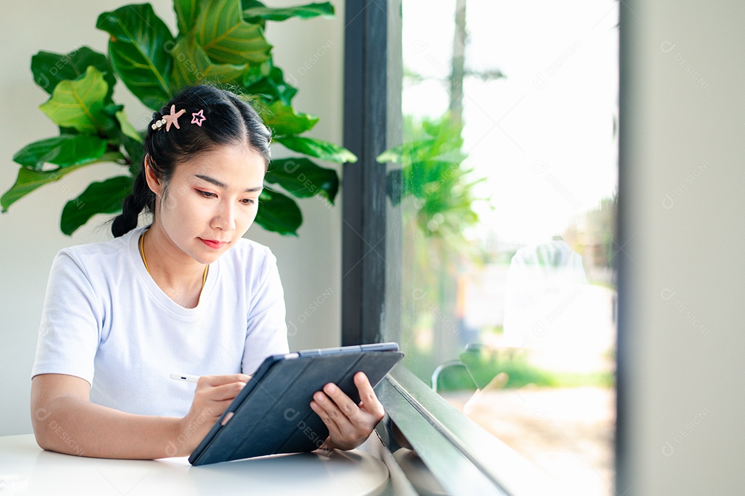Mulher asiática sentada segurando um tablet