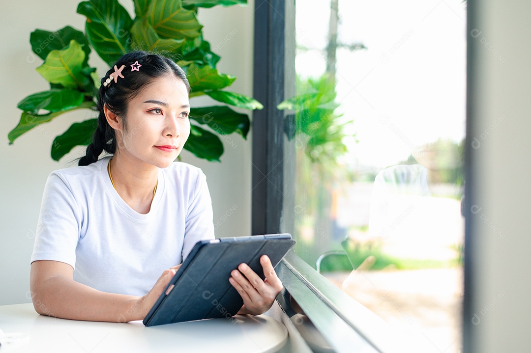Mulher asiática sentada segurando um tablet