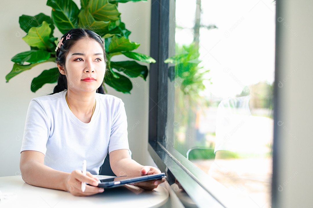 Mulher asiática sentada segurando um tablet