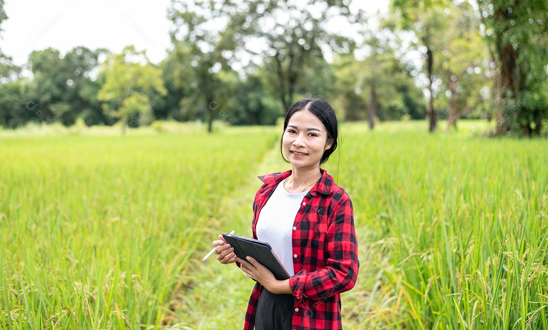 Mulher agricultora segurando um tablet e fazendo analise das plantações