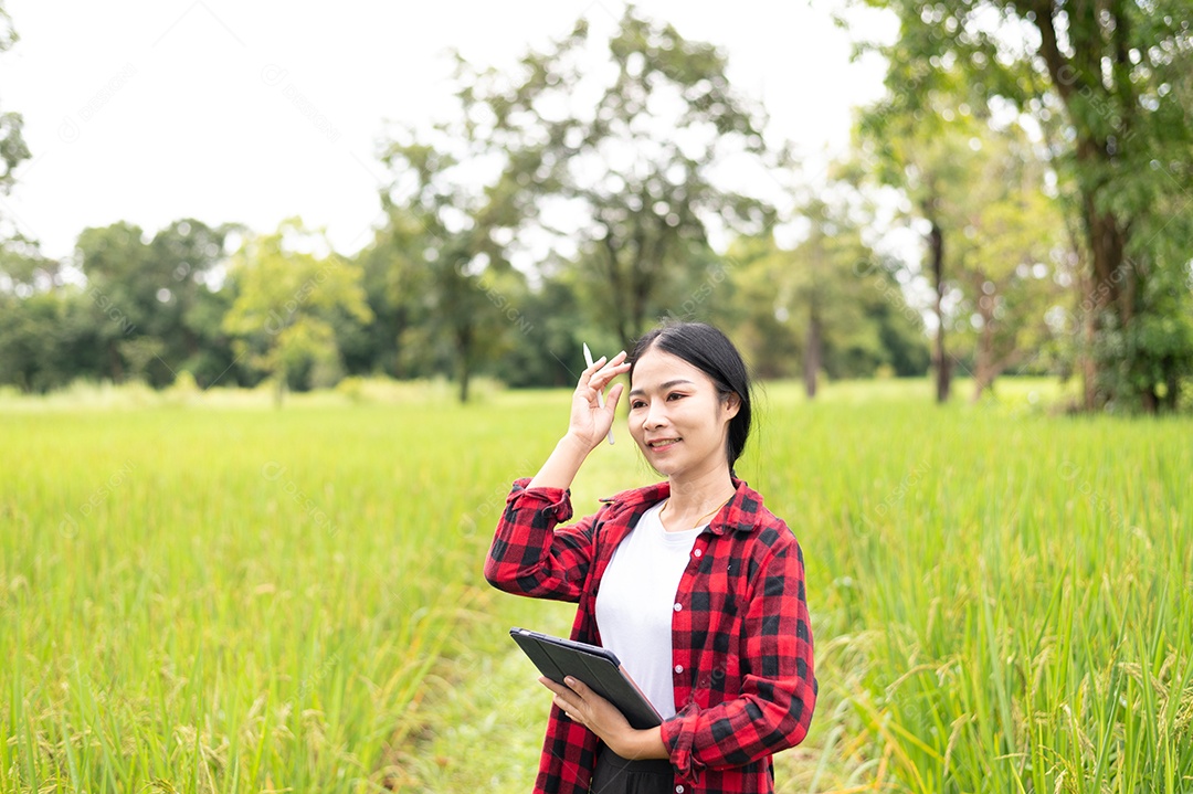 Mulher agricultora segurando um tablet e fazendo analise das plantações