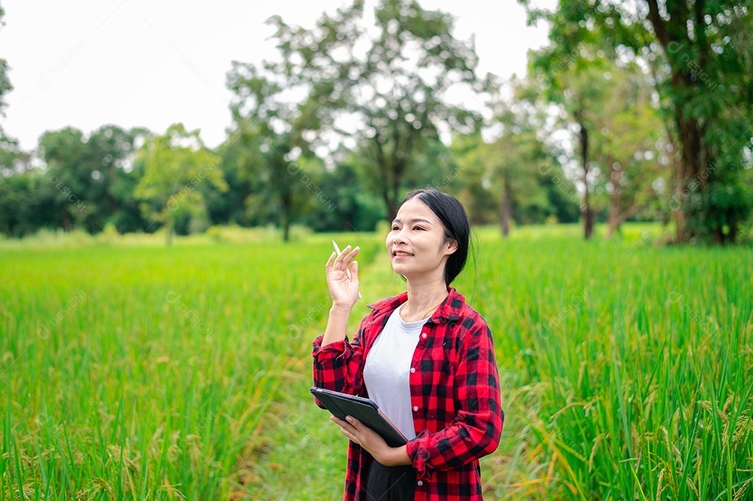 Mulher agricultora segurando um tablet e fazendo analise das plantações