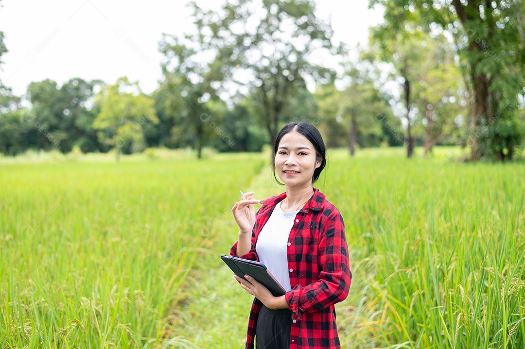 Mulher agricultora segurando um tablet e fazendo analise das plantações