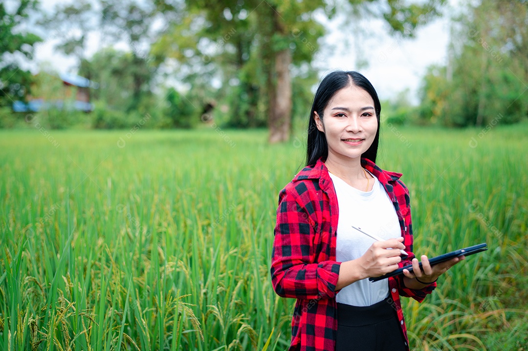 Mulher agricultora segurando um tablet e fazendo analise das plantações