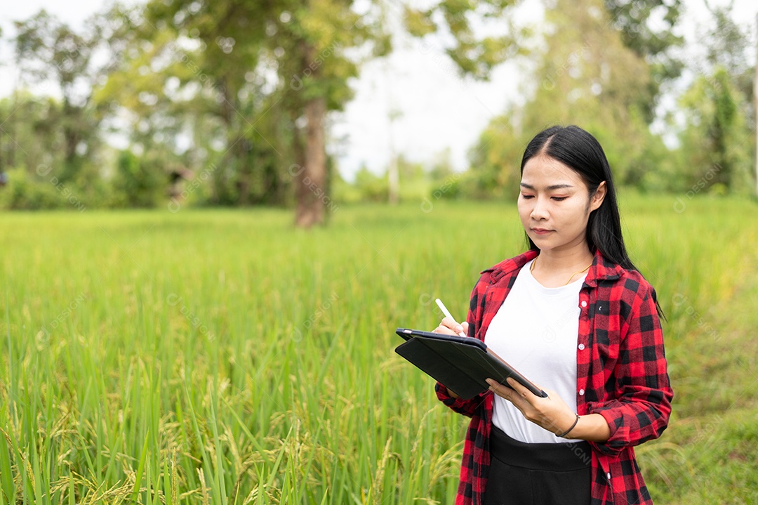Mulher agricultora segurando um tablet e fazendo analise das plantações