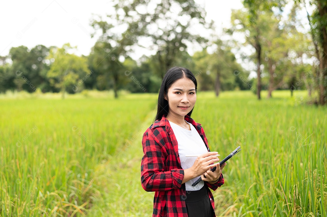 Mulher agricultora segurando um tablet e fazendo analise das plantações