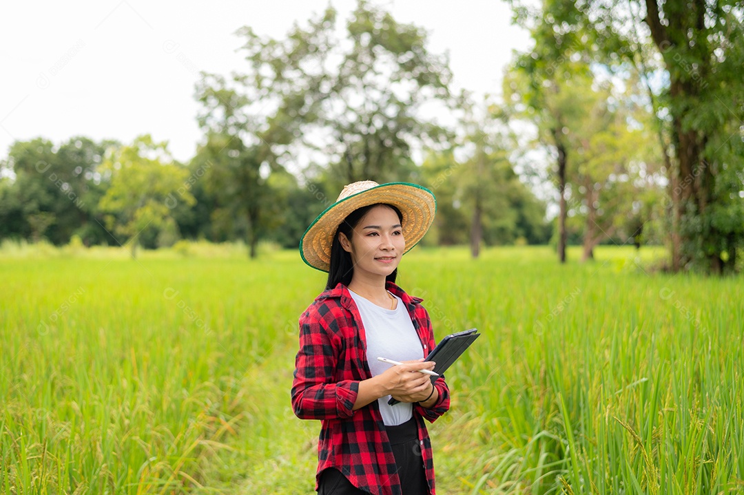 Mulher agricultora segurando um tablet e fazendo analise das plantações
