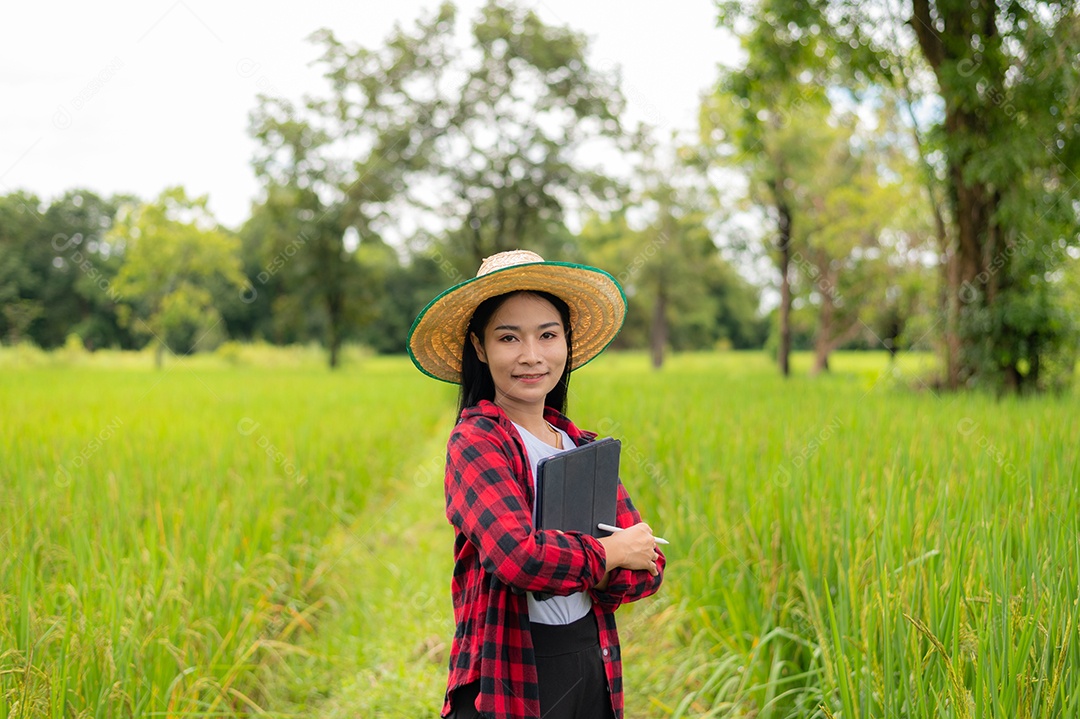 Mulher agricultora segurando um tablet e fazendo analise das plantações