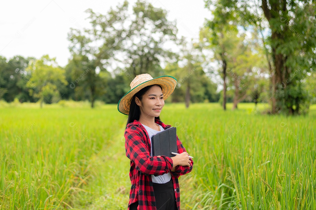 Mulher agricultora segurando um tablet e fazendo analise das plantações
