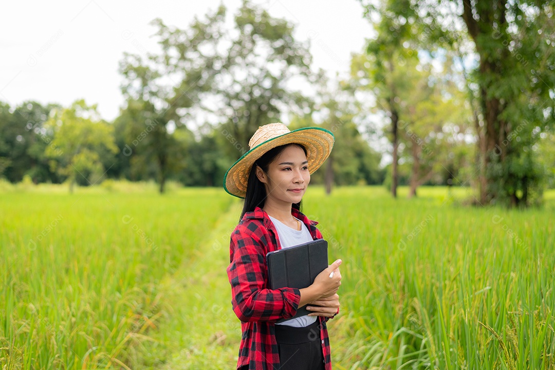 Mulher agricultora segurando um tablet e fazendo analise das plantações