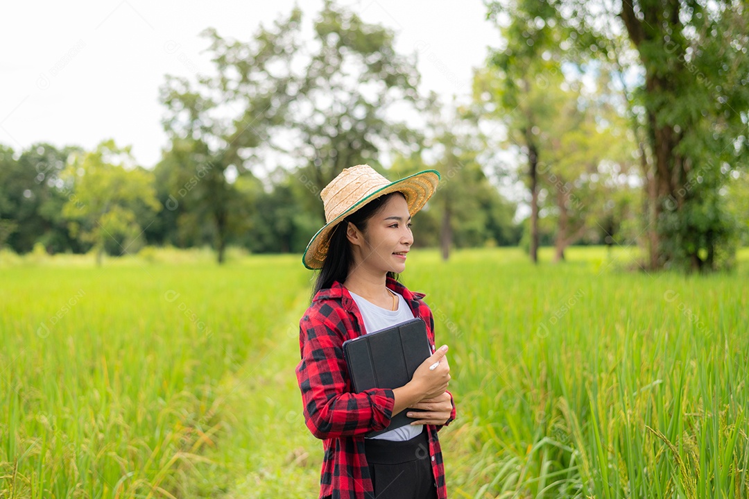 Mulher agricultora segurando um tablet e fazendo analise das plantações